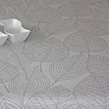 Amberes Jacquard, grå blad.  Jacquardvävd textilvaxduk med grå streckade blad på naturfärgad bakgrund